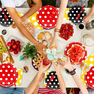 Close-up of colorful polka dot party plates, napkins, and forks in a lively social setting