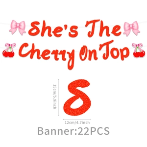 Close-up of red glitter 'She's The Cherry On Top' party banner with pink bows and cherry charms
