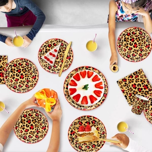 Red leopard print party tableware set with paper plates, cups and napkins on table