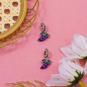DIY jewelry pair of purple grape charms with green enamel leaves on pink background