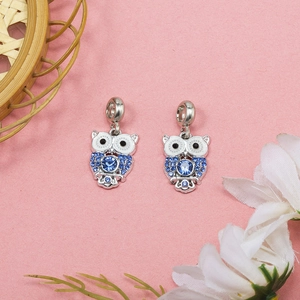 Sparkling silver owl pendants with blue crystals and enamel on a pink background