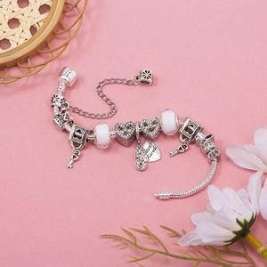 Silver beaded bracelet with pink charms, heart pendant, and crown on a pink background