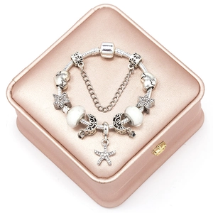 Elegant silver snake chain bracelet with starfish and moon charms on rose gold box