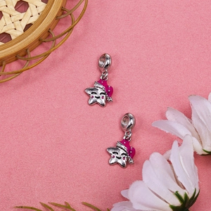 Silver star charms with pink enamel hats for DIY bracelets on pink floral background