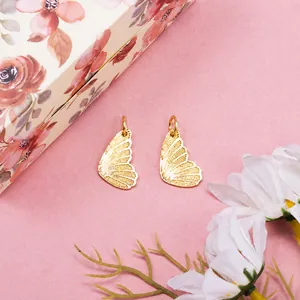 Golden butterfly wing pendants in pair for DIY jewelry making on pink background