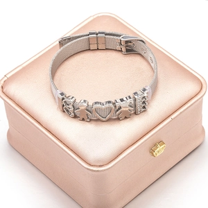 Silver mesh bracelet with heart and crown charms displayed on a pink jewelry box