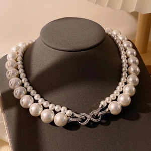 Détail du collier de perles double rang avec un fermoir infini orné de diamants brillants