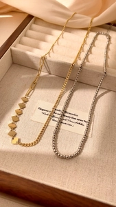 Detailed view of silver and gold necklaces in a wooden jewelry display tray