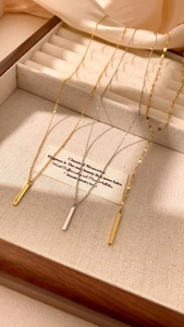 Close-up of gold and silver bar pendant necklaces on a wooden jewelry display case