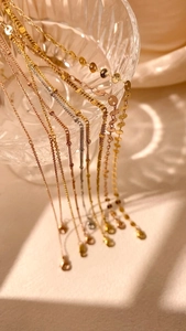 Artistic detail of gold and silver layered necklaces draped on a glass vessel