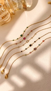 Detailed macro view of gold chain bracelets with colorful square and round gemstones