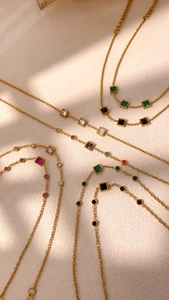 Macro detail of gold-plated chains with colorful geometric square and round gemstones