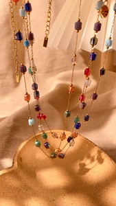 Detailed macro view of bohemian double-layer necklace with multi-color crystal beads on gold chain