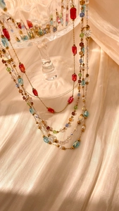Detail of layered bohemian necklace with colorful crystal beads on elegant satin background