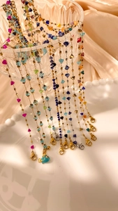 Detail of colorful beads and enamel fish charm draped over an embossed glass cup