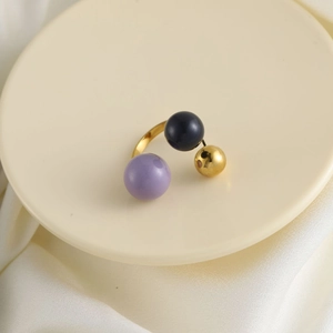 Dettaglio dell'anello dorato con perline multicolori su un vassoio crema