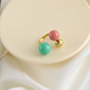 Dettaglio anello dorato aperto con perline rosa e verde menta su espositore elegante
