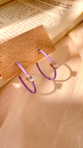 Detail of lavender enamel C-shaped hoop earrings with a sparkling heart zircon center