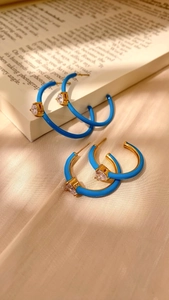 Macro shot of blue enamel heart earrings with sparkling cubic zirconia on silk fabric