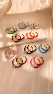 Multi-colored enamel C-shaped gold-plated earrings set with zircon accents on a tray
