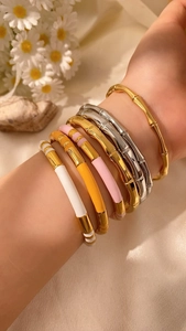 Dettaglio macro di bracciali in smalto colorato a forma di bambù con placcatura oro