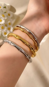 Dettaglio di bracciali in metallo a forma di C stile bambù in oro e argento