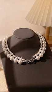 Detalle de collar de doble capa de perlas blancas con cierre de infinito y cristales brillantes