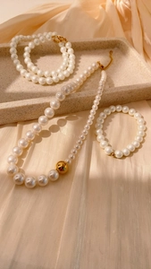 Detalle de collares de perlas a capas con cuentas doradas sobre elegante fondo raso