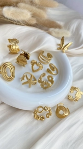 Macro detail of gold open rings set with butterfly, starfish and floral leaf motifs
