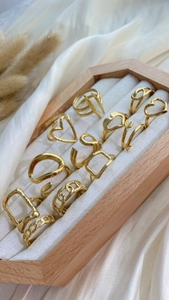 Set of eleven gold minimalist adjustable rings with heart and geometric textures on silk