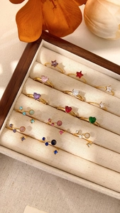 Primo piano di anelli d'oro a cuore e stella con zirconi colorati in un portagioie