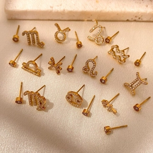 Boucles d'oreilles constellation dorées avec zircones sur décor de pierre blanche