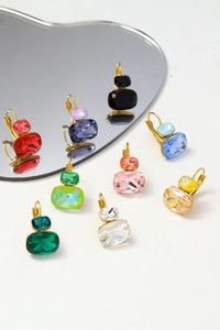 Detalle macro de pendientes de circonita cuadrada de colores con ganchos dorados en espejo
