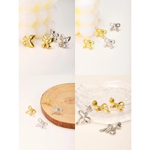 Close-up of bow knot stud earrings in polished gold and silver metallic finishes