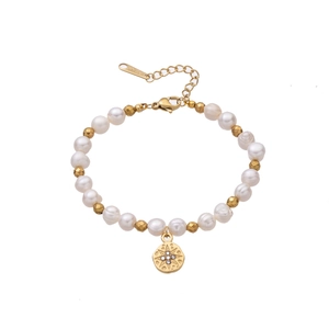 Dettaglio del bracciale di perle con ciondolo a stella dorato e chiusura a moschettone