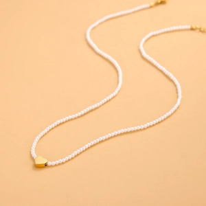 Detalle de un collar de perlas con colgante de corazón dorado pulido y cierre de langosta