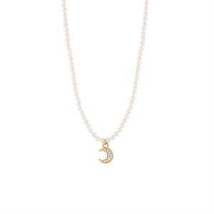 Detalle de collar de perlas con colgante de luna creciente dorada y circonitas brillantes