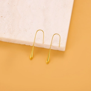 Detailansicht eleganter goldener Tropfenohrringe auf Marmor mit natürlichem Licht