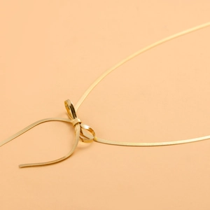 Dettaglio di una collana a catena a serpente dorata con un design unico a fiocco