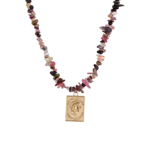 Macro detail of natural stone beaded necklace with a golden vintage relief coin pendant