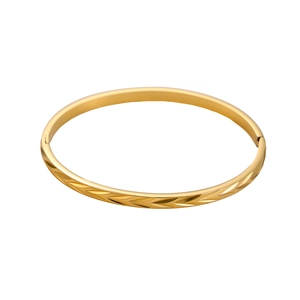 Macro shot of gold-plated bangle with detailed wheat pattern engraving and clasp closure