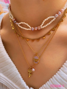 Close-up of layered vintage necklace with pink pearls, gold butterfly and rose pendants