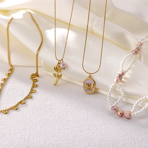Elegant gold necklaces and pink pearl choker set displayed on luxury white silk fabric