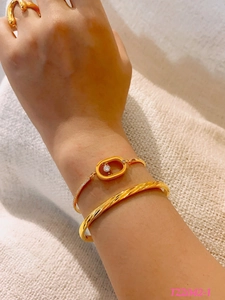 Detalle de pulseras doradas en capas con circón deslizante y brazalete retorcido
