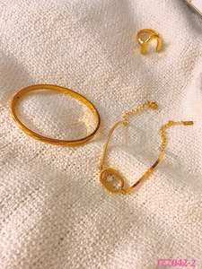Detalle de conjunto pulsera dorada con diamante deslizante y brazalete sobre tejido blanco