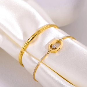 Elegante conjunto de brazaletes dorados con textura espiral y dije de cristal en seda