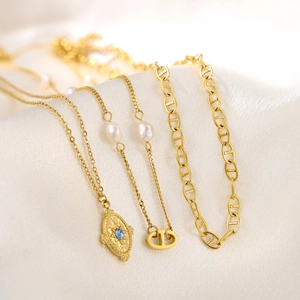 Minimalist gold necklaces with pearls and blue stone pendant on silk fabric