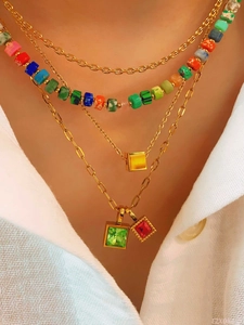 Detail of four-layered gold necklace with colorful beads and geometric pendants