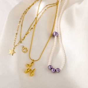 Dettaglio del ciondolo cane palloncino e collane con perle viola su seta bianca
