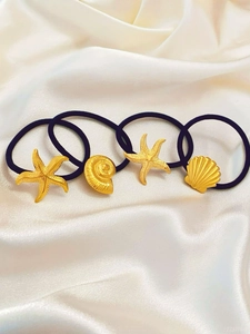 Détail de quatre breloques dorées marines avec étoile de mer et coquillage sur élastiques